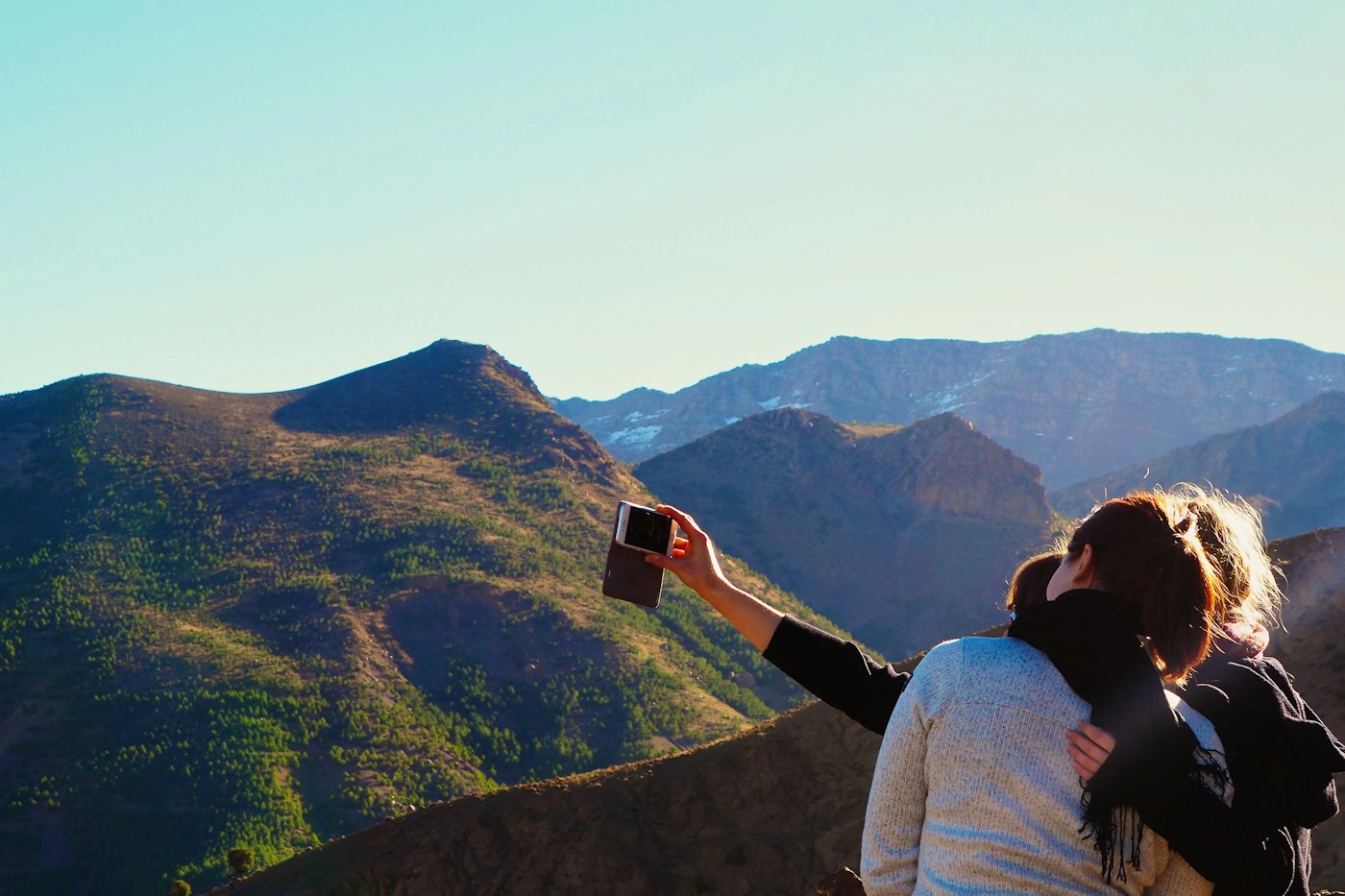 Two friends taking a selfie in front of mountain ridges